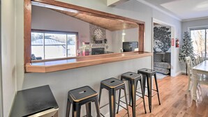 A kitchen with a wooden countertop, three bar stools, a clock, and a fireplace. - New Hampshire Home w/ Private Beach, Dock & Rafts! (Center Barnstead)