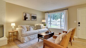 A living room with a sofa, a coffee table, a chair, a lamp, and artwork on the wall. - Lovely Vancouver Retreat w/ Home Gym! (Vancouver)
