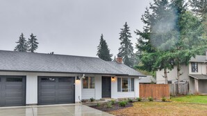 A residential house with a garage, a front porch, and a well-maintained lawn. - Lovely Vancouver Retreat w/ Home Gym! (Vancouver)
