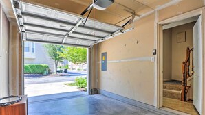 Eine Garage mit Betonboden, einer hölzernen Sitzbank und einer Tür zu einer Treppe.