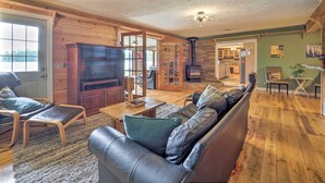 A cozy living room with a fireplace, leather sofa, and wooden flooring. - 13 Mi to Dtwn: Lakefront Cottage w/ Dock (Traverse City)