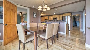 A dining area with a wooden table and chairs, a chandelier, and a view into the kitchen. - 13 Mi to Dtwn: Lakefront Cottage w/ Dock (Traverse City)