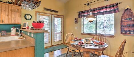 A dining area with a wooden table, chairs, and a red bowl on the counter.