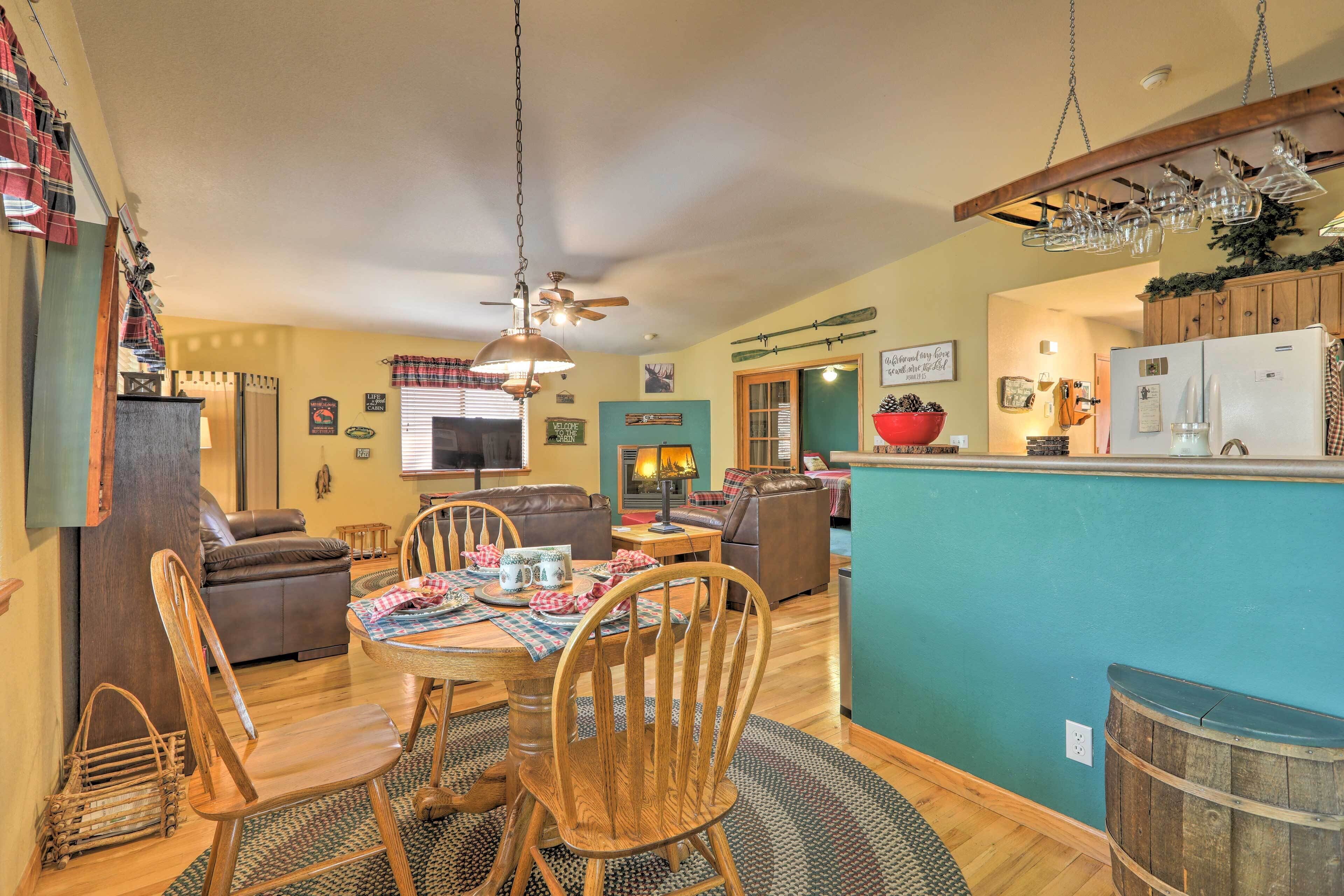 A cozy living room with a dining area, wooden furniture, and a kitchen with a blue accent wall.