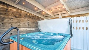 A hot tub with a wooden exterior and a white interior, surrounded by a wooden wall and a white fence.