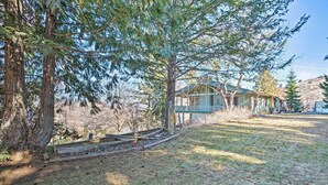 A rustic cabin with a porch, surrounded by tall trees and a clear sky.