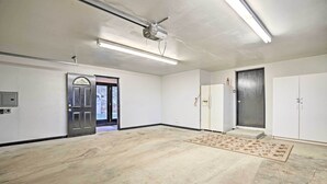 A spacious room with a large open area, a door leading outside, and a ceiling fan.