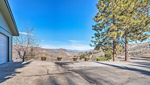 A driveway leading to a garage with a clear view of mountains and a pine tree.