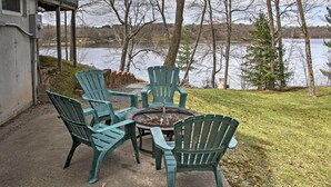 A patio with four green Adirondack chairs and a round table with a fire pit in the center, overlooking a lake. - Cozy Balsam Lake Home: Deck, Private Dock + Kayaks (Balsam Lake)