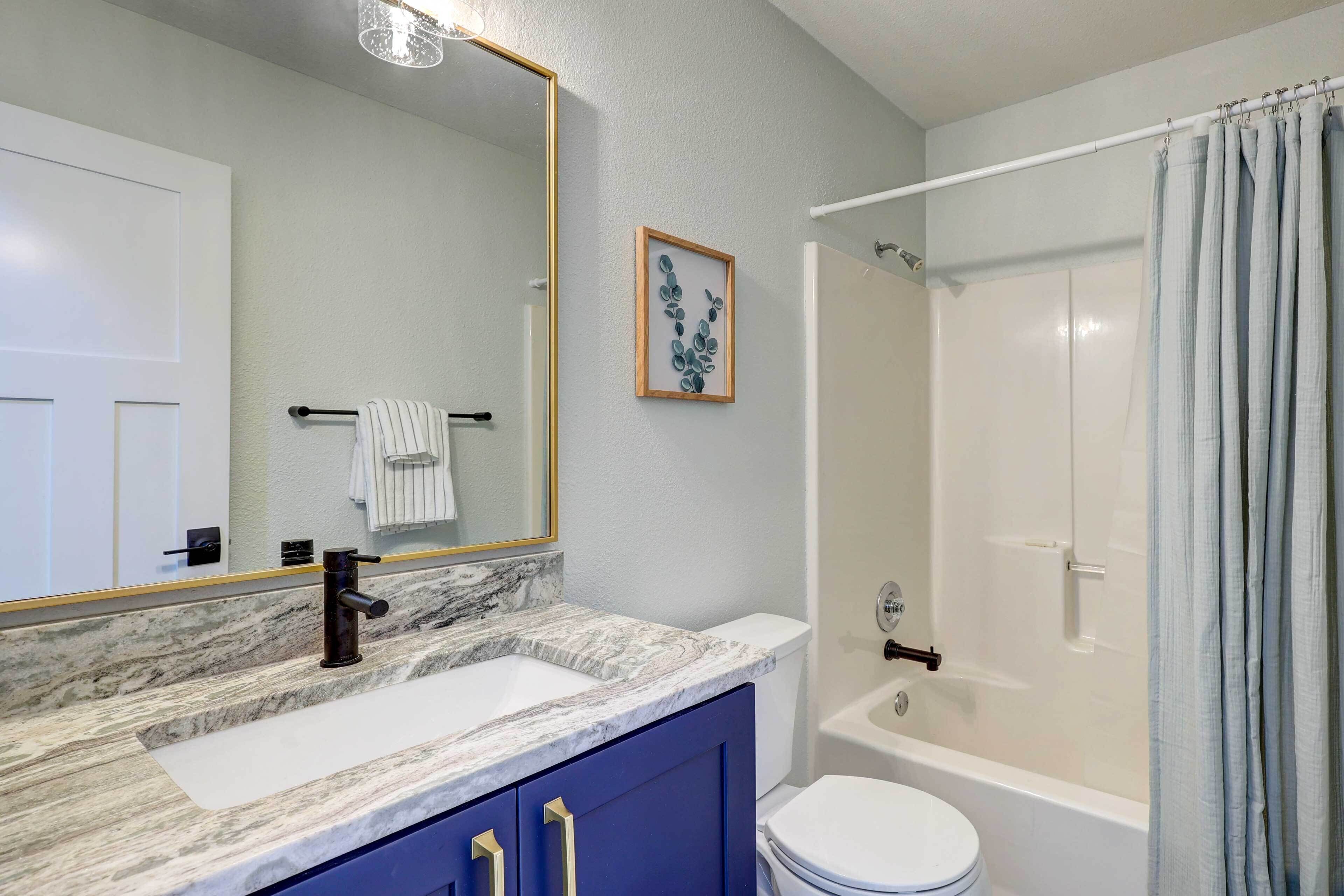 Une salle de bain avec un lavabo en marbre, des toilettes blanches, une baignoire et un rideau de douche.