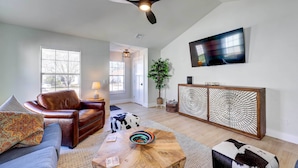 A modern living room with a leather sofa, a wooden coffee table, and a TV mounted on the wall.