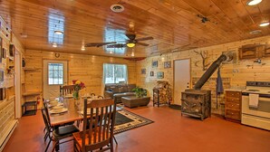 A log cabin interior with a dining area, living room, and kitchen. - 400-acre Outdoor Enthusiast's Lodge in Mancelona! (Mancelona)