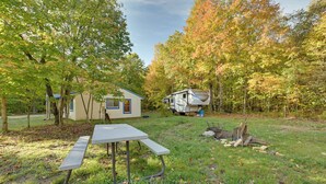 A campsite with a picnic table, a small cabin, and a recreational vehicle. - 400-acre Outdoor Enthusiast's Lodge in Mancelona! (Mancelona)