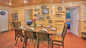 A dining area with a wooden table set for four, surrounded by chairs. - 400-acre Outdoor Enthusiast's Lodge in Mancelona! (Mancelona)