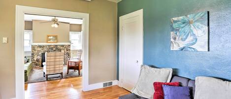 A living room with a sofa, cushions, a coffee table, and a painting on the wall.