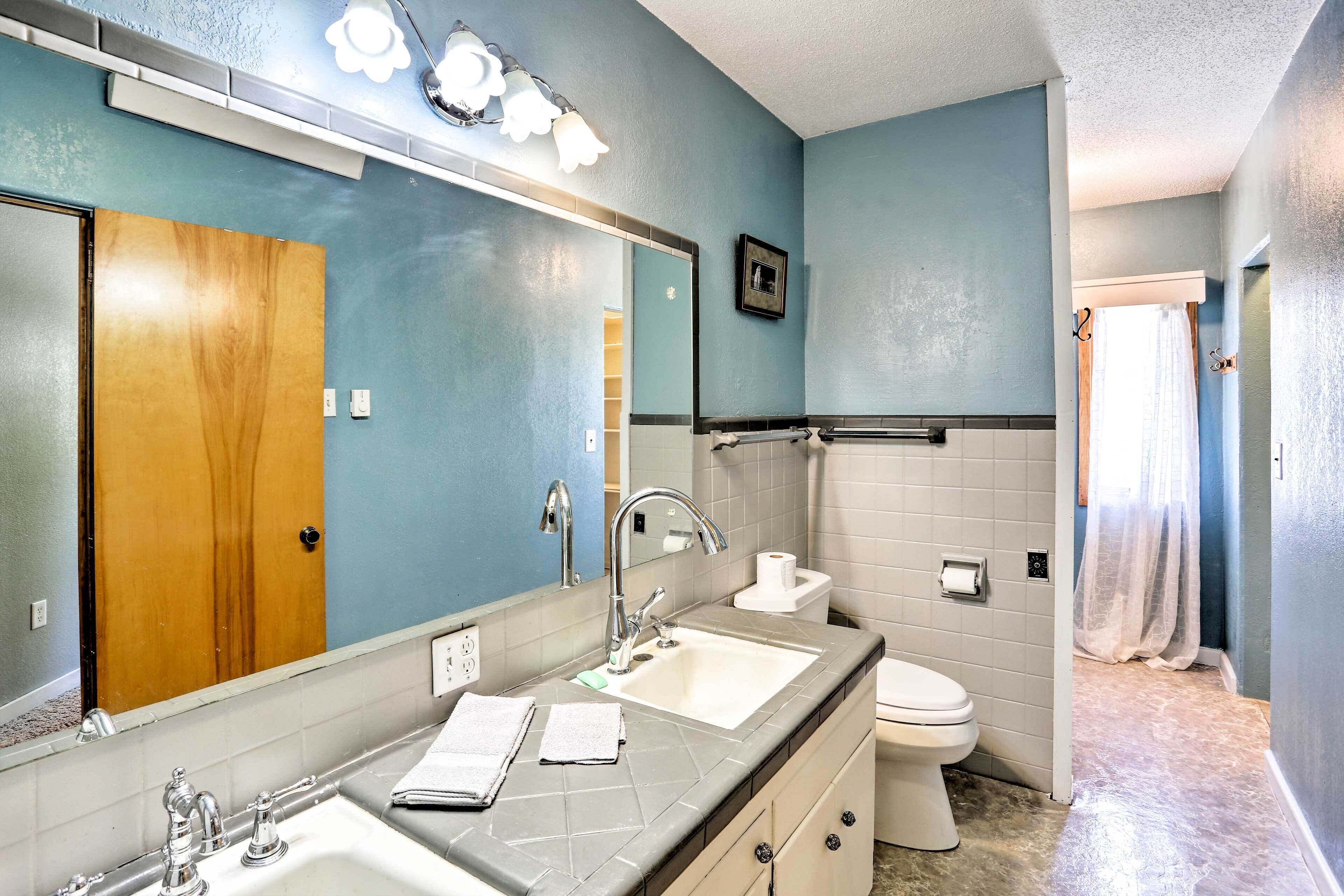 Un baño con un espejo grande, dos lavamanos, un inodoro y una cortina de ducha.