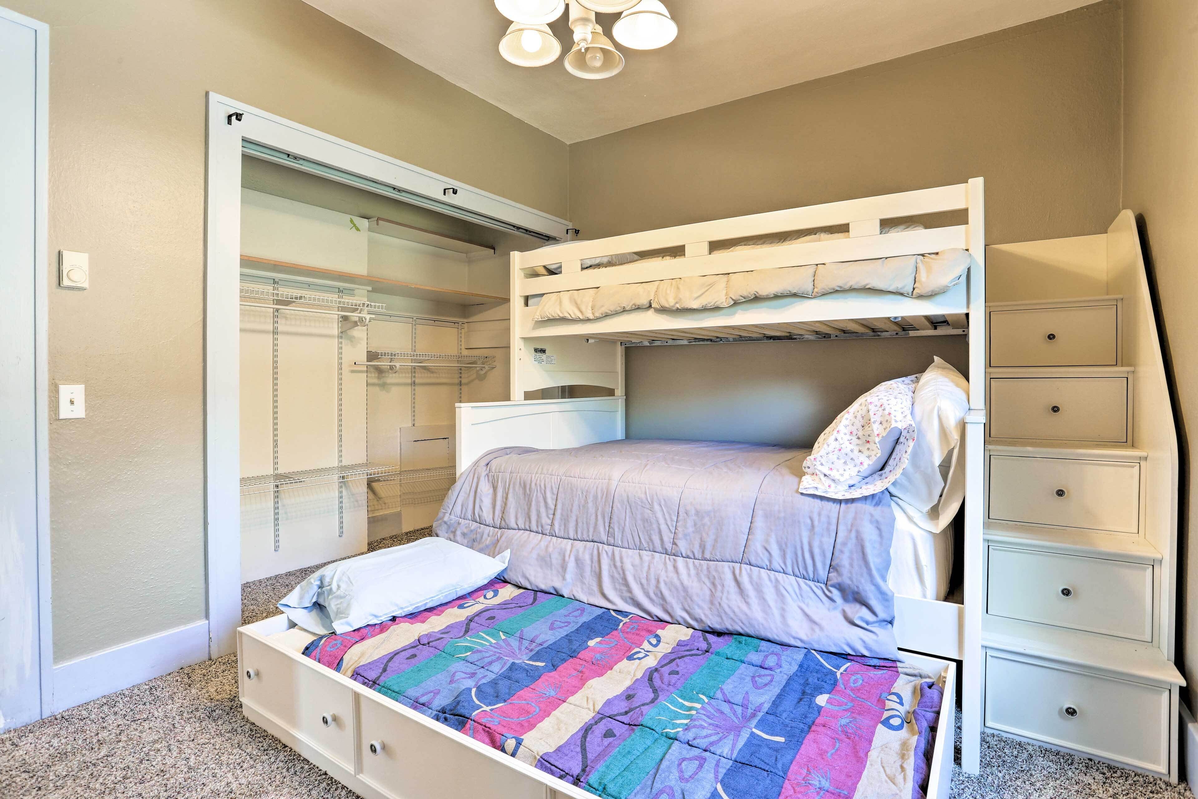 Una cama litera con una cama inferior, una mesita de noche, un aparador y un armario con puerta corredera.
