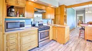 Une cuisine avec des meubles de rangement en bois, une cuisinière, un four à micro-ondes et une machine à café.