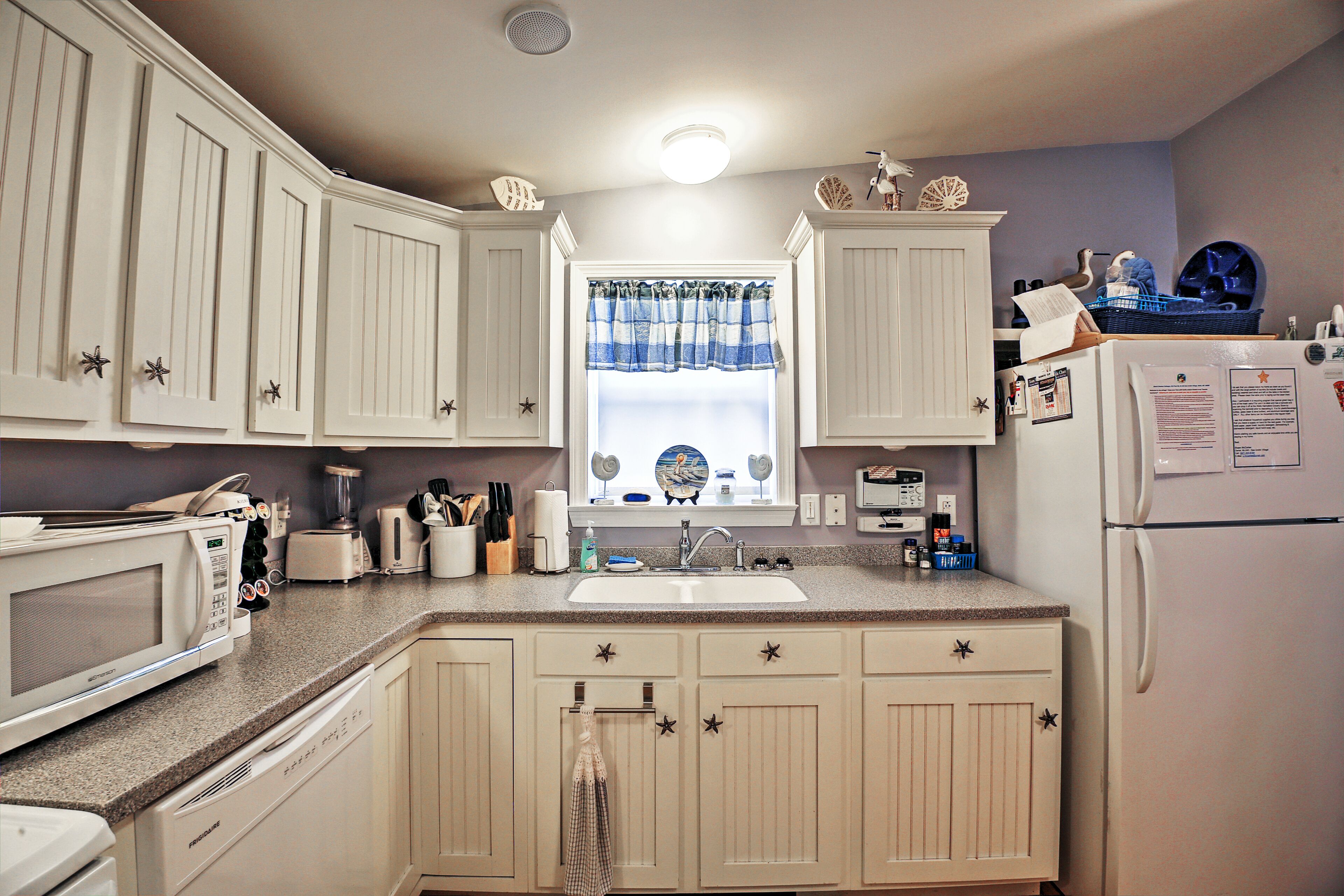 A kitchen with white cabinets, a microwave, a sink, and a refrigerator.
