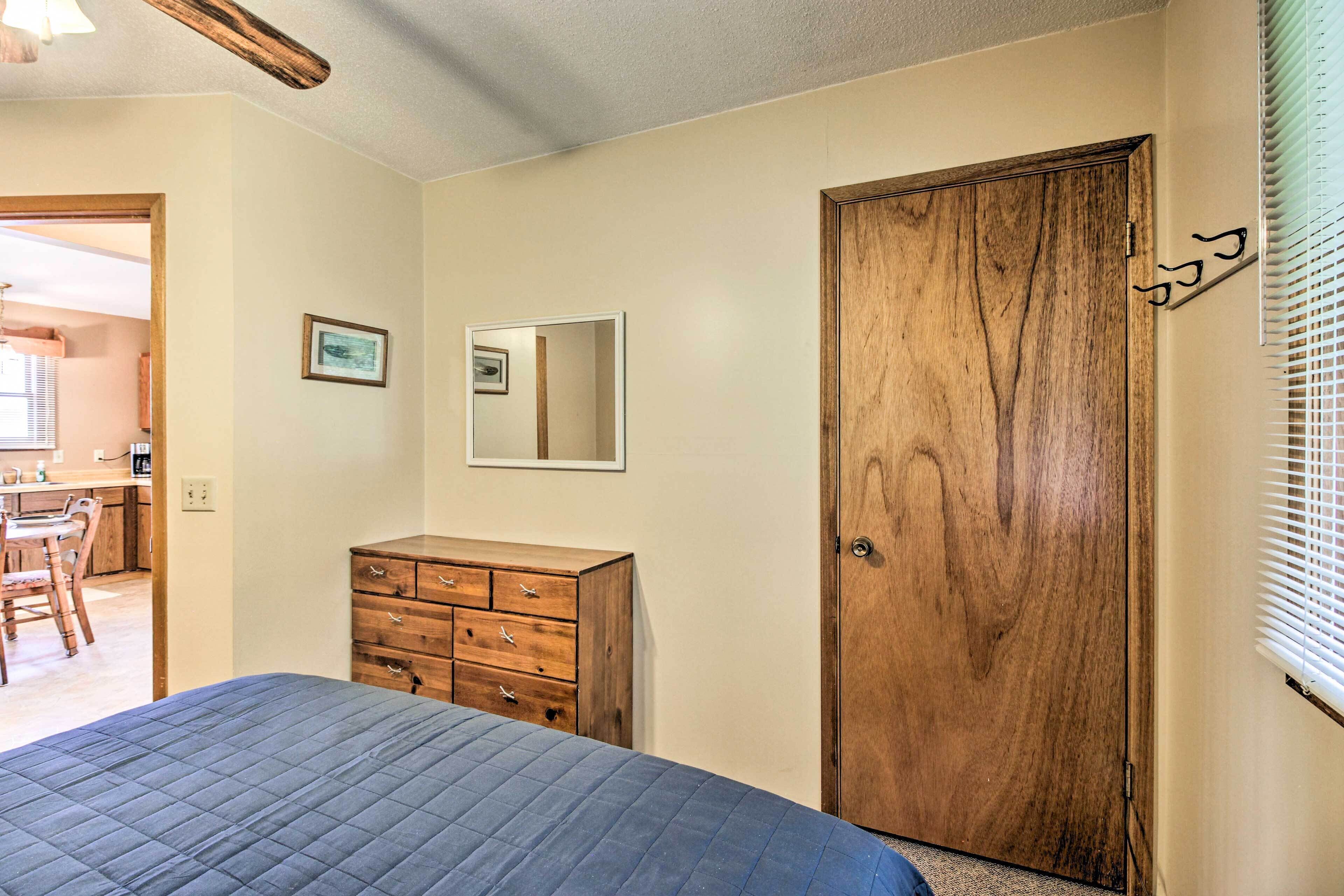 Een slaapkamer met een bed, een houten dressoir en een deur.