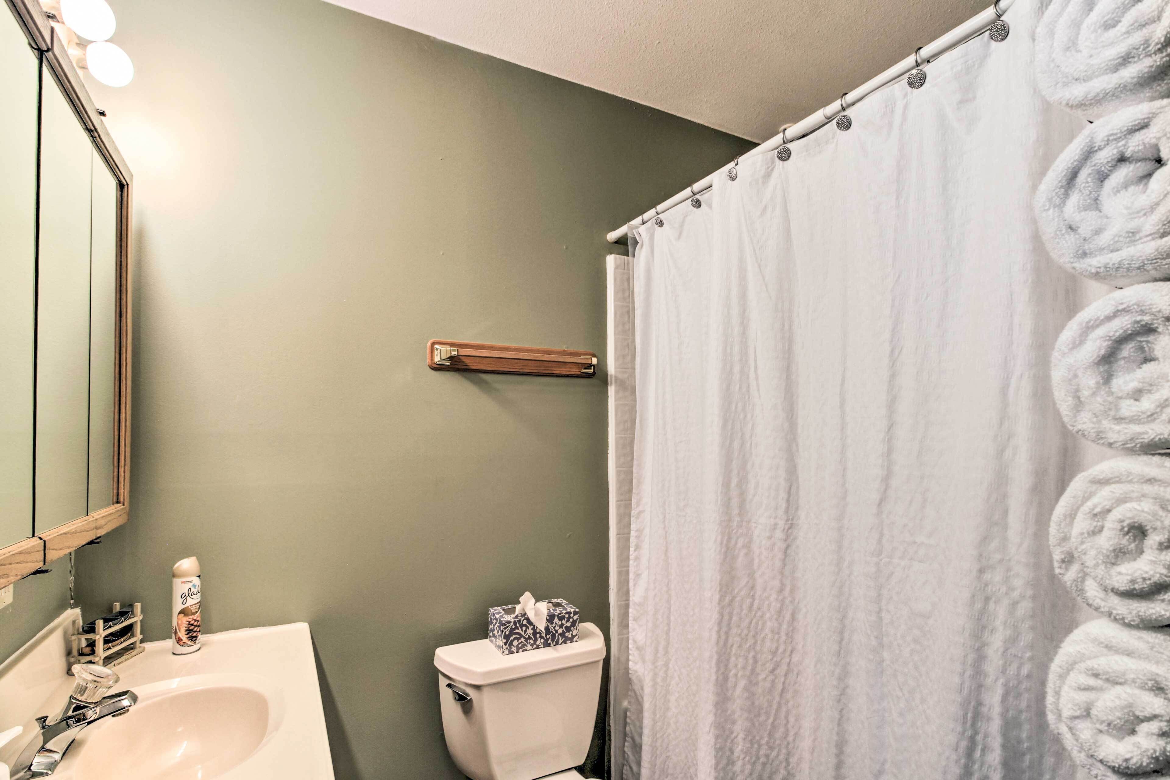 Une salle de bain avec un lavabo blanc, des toilettes, un miroir et un rideau de douche.