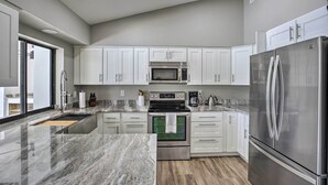 A modern kitchen with white cabinets, stainless steel appliances, and a marble countertop. - Canal-front Cape Coral Home: Pool & Patio (Cape Coral)