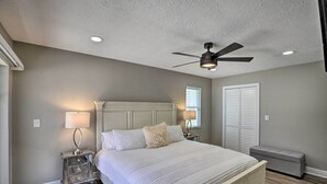 A bedroom with a bed, nightstands, a ceiling fan, and a window. - Canal-front Cape Coral Home: Pool & Patio (Cape Coral)