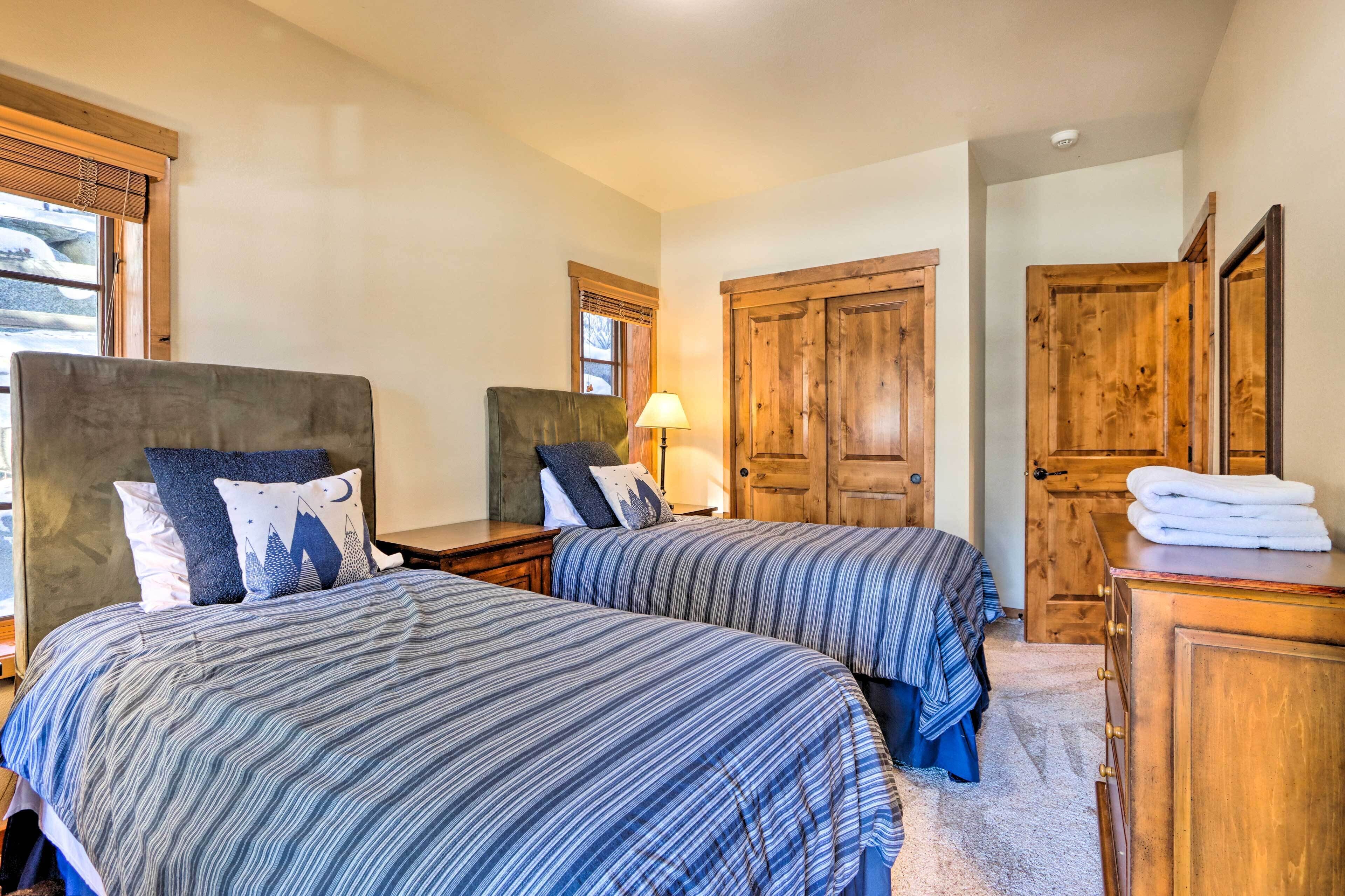 A bedroom with two beds, wooden wardrobes, and a window with blinds.