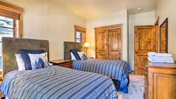 A bedroom with two beds, wooden wardrobes, and a window with blinds.