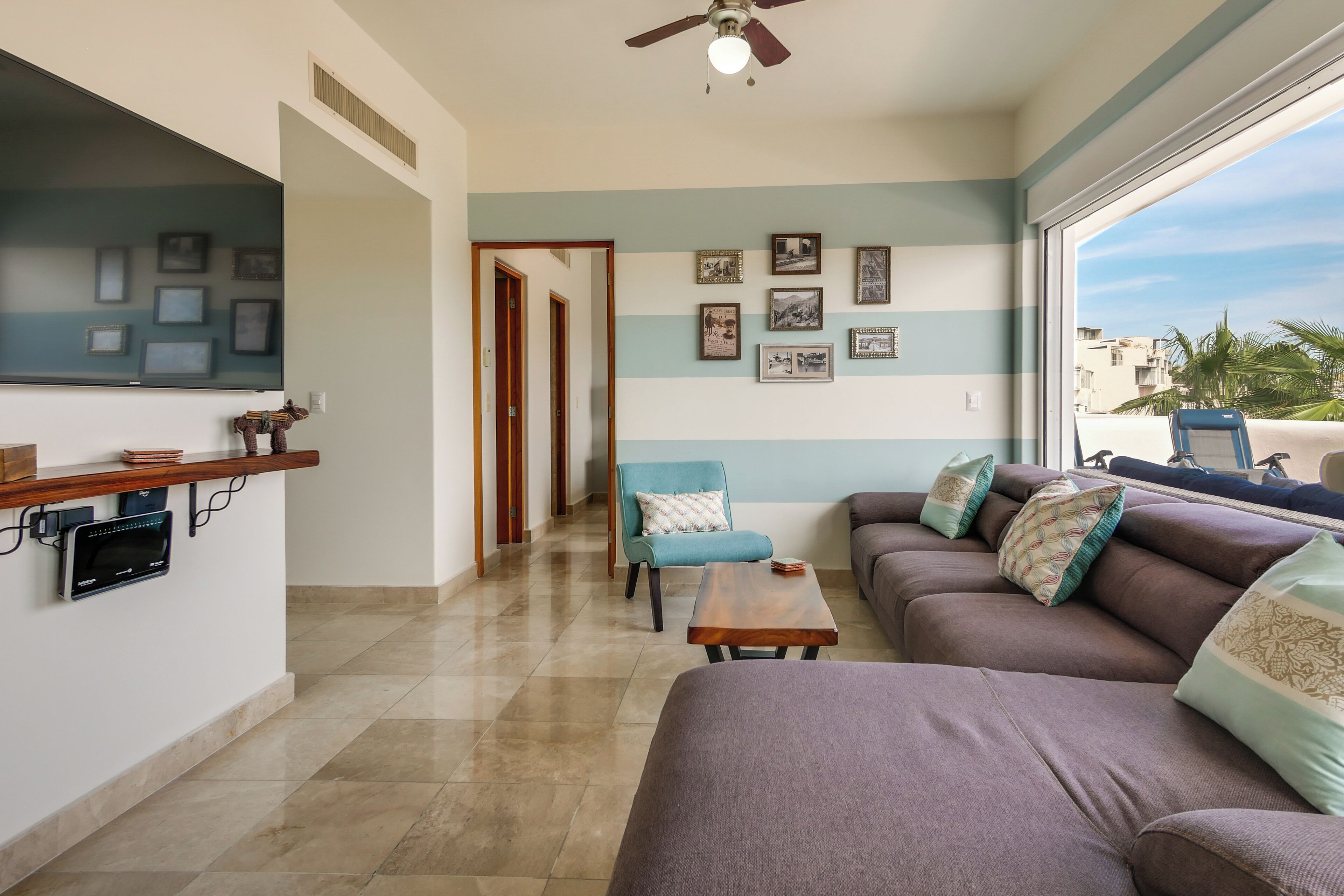 A living room with a sofa, a coffee table, and a TV mounted on the wall.