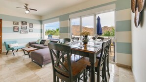 A spacious living area with a dining table set for four, a sofa, and a ceiling fan. - Chic Cabo Condo - Walk to Marina & Downtown! (Cabo San Lucas)