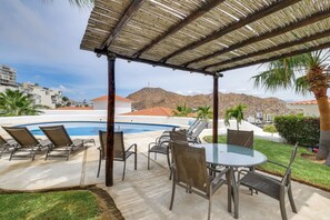 Et overdækket udendørsområde med en pool, liggestole og et bord med stole.