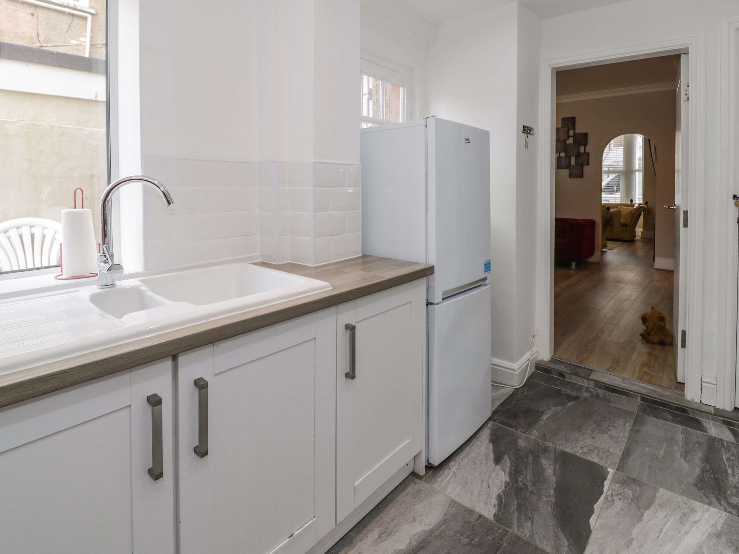 Una cocina moderna con armarios blancos, un lavabo y un refrigerador.