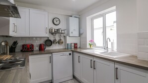 A modern kitchen with white cabinets, a dishwasher, a sink, and a window providing natural light.