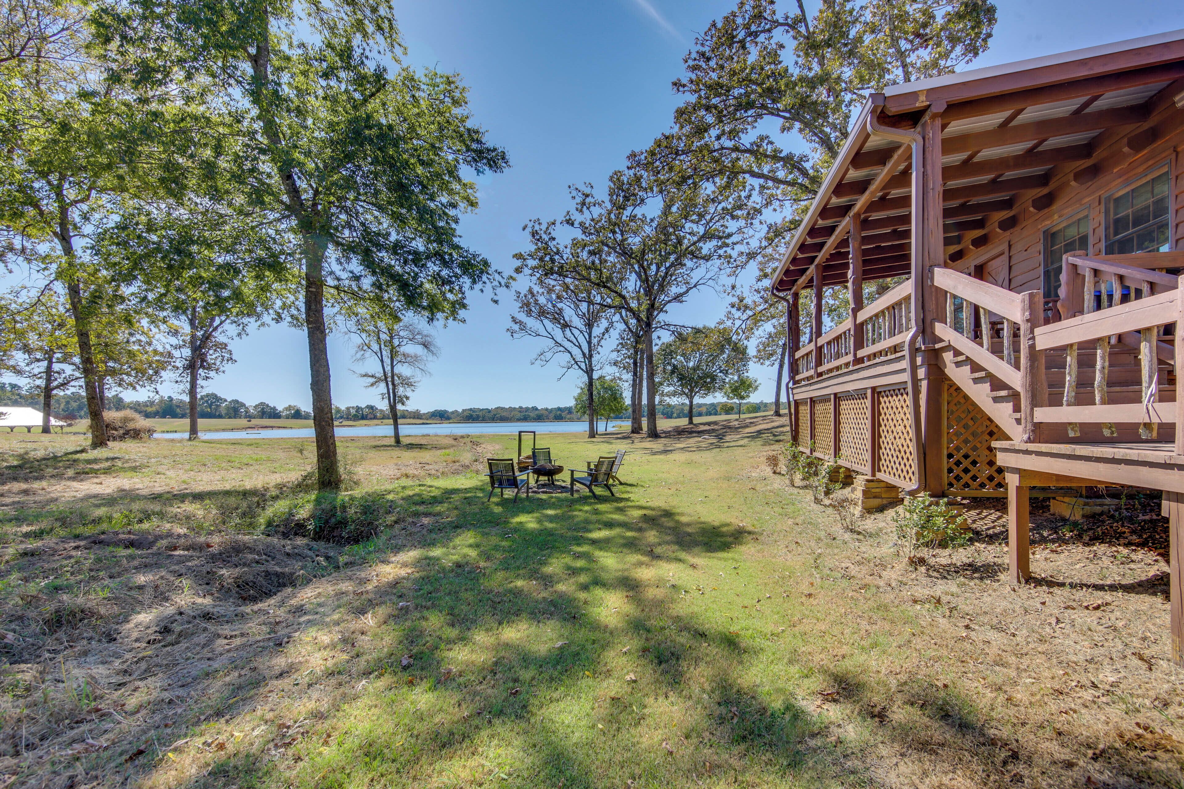 A wooden cabin with a deck overlooking a lake, surrounded by trees.