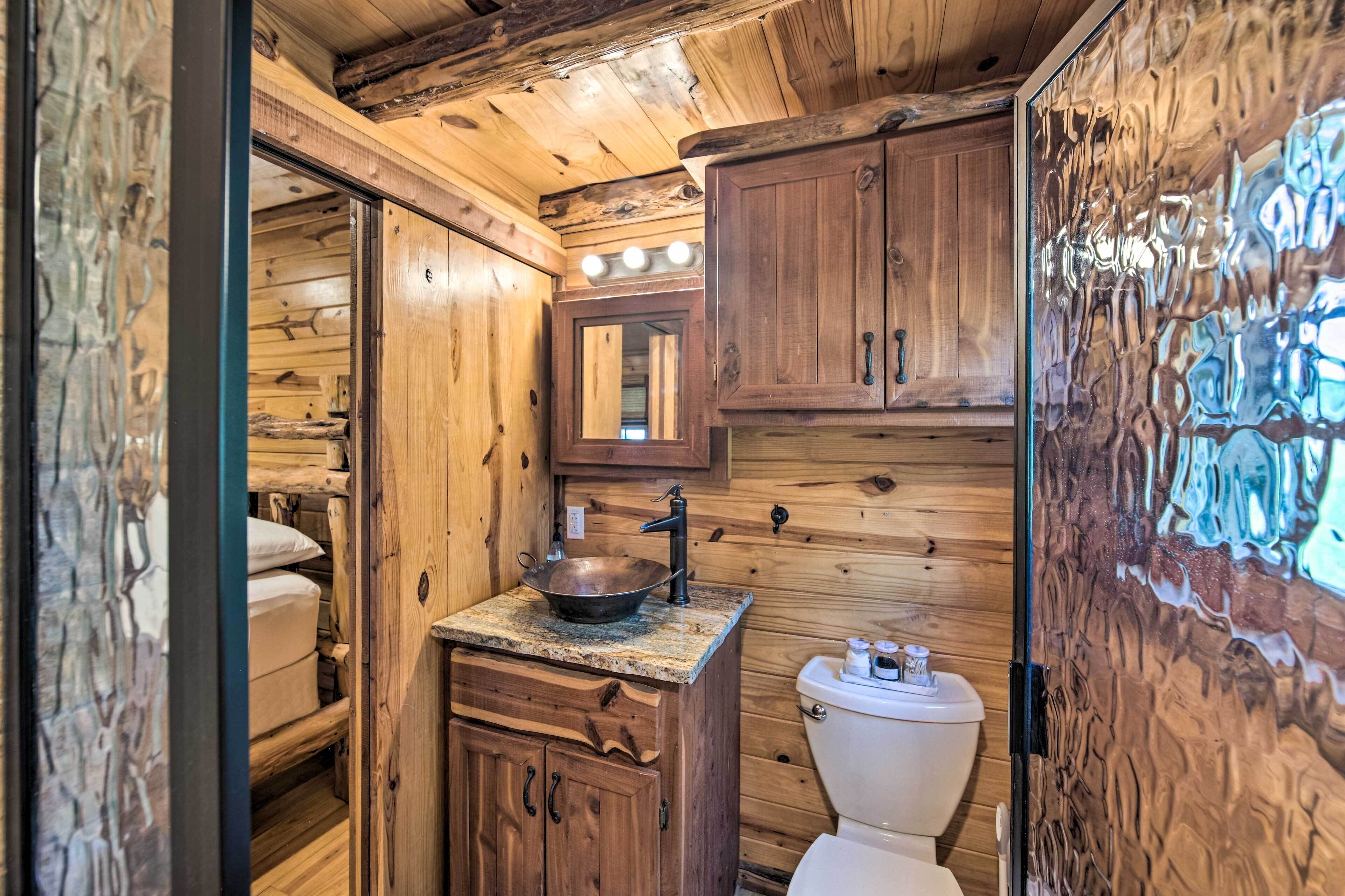 A wooden cabin bathroom with a sink, mirror, and toilet.