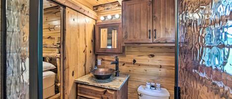 A wooden cabin bathroom with a sink, mirror, and toilet.