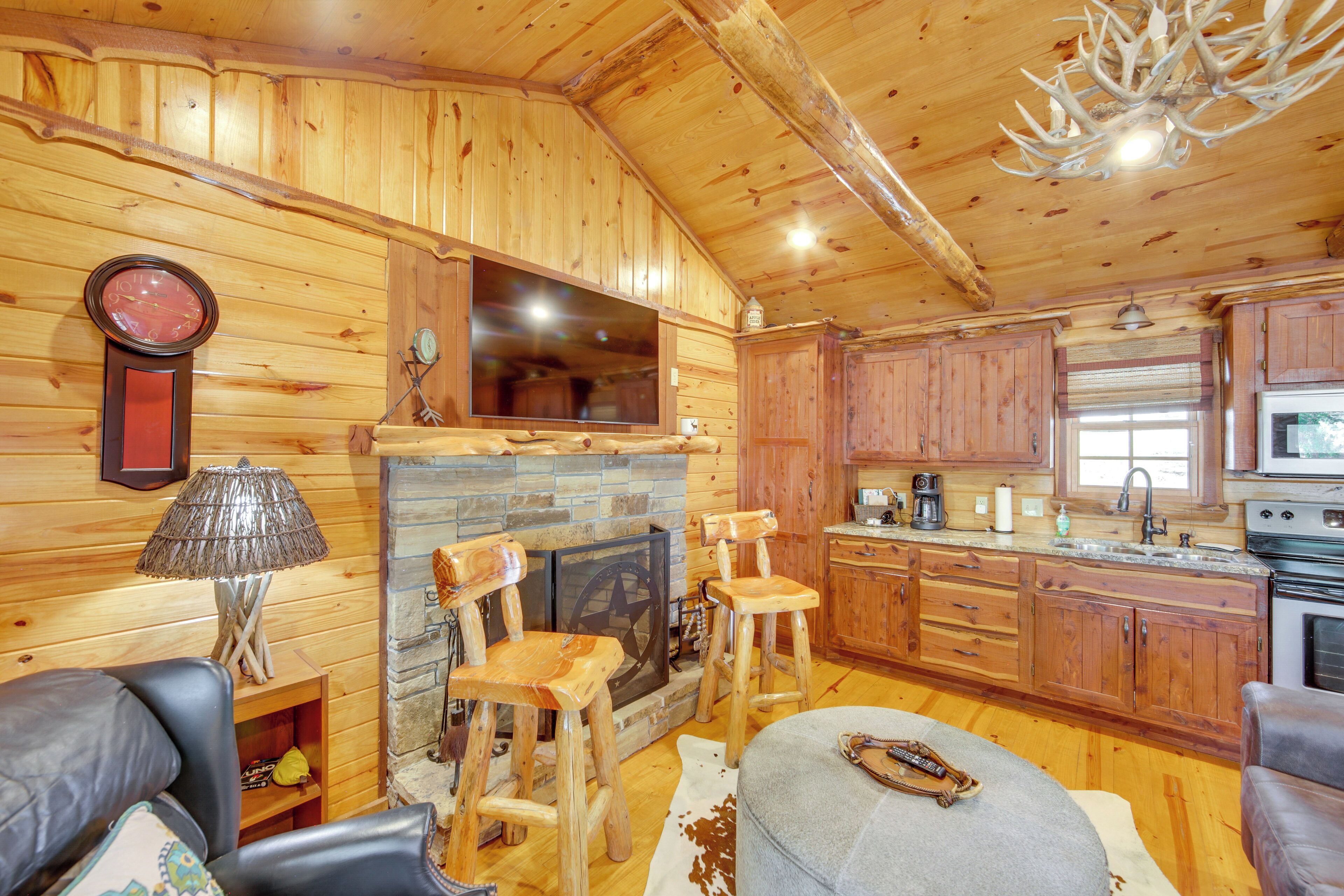 Ein Holzblockhaus-Interieur mit Kamin aus Stein, Holzmöbeln und einer Küchenzeile.