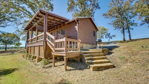 Une cabane en bois dotée d’un porche et d’un escalier menant à l’entrée.