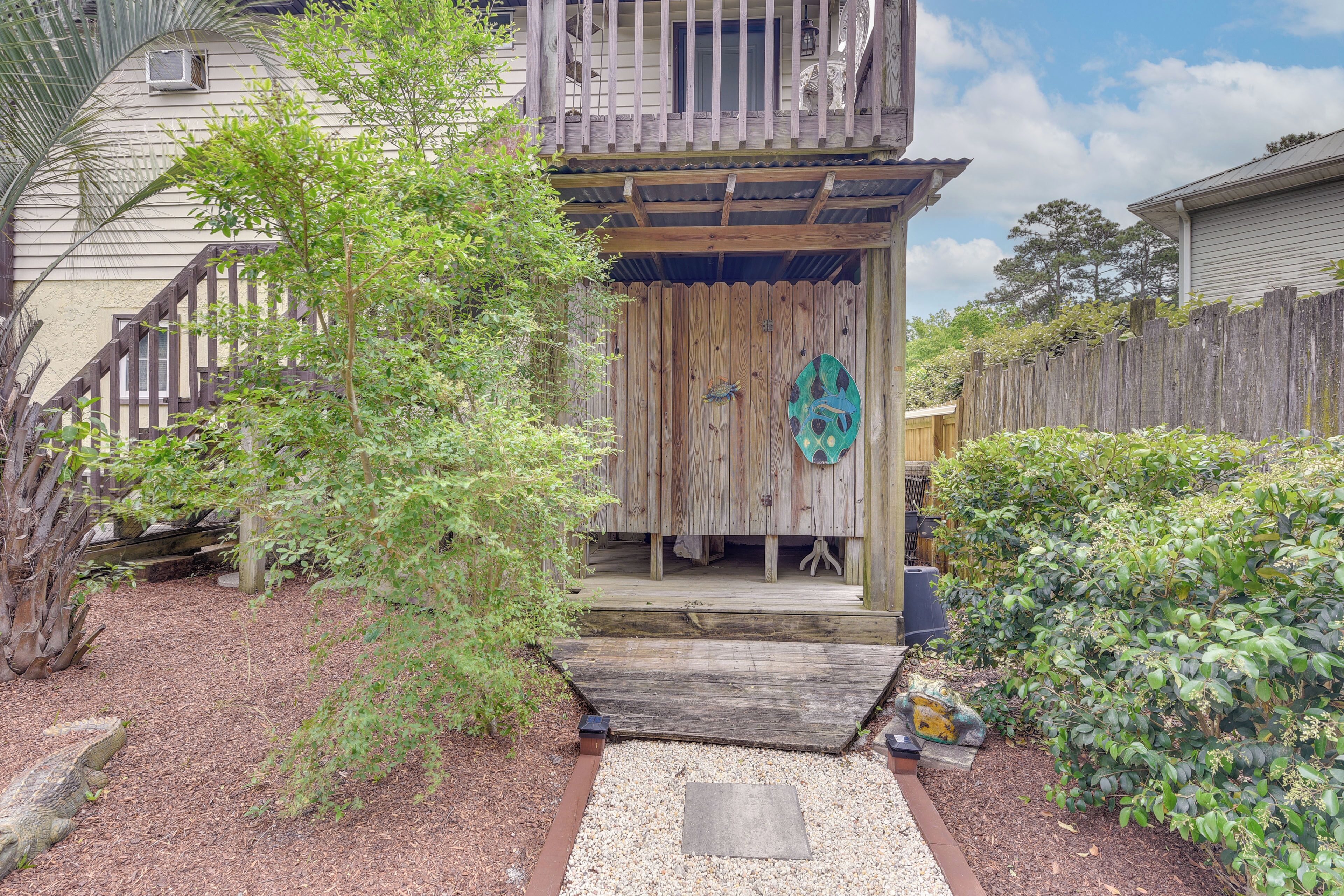 A wooden house with a porch, a small deck, and a fenced yard.