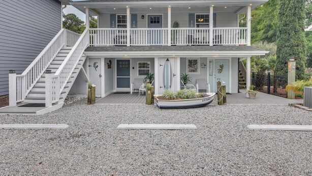 A two-story house with a covered porch, a boat in front, and a gravel driveway. - 1 Mi to Ocean Isle Beach! Studio w/ Outdoor Oasis (Ocean Isle Beach)