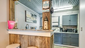 A kitchen with a wooden island, bar stools, a microwave, and cabinets. - 1 Mi to Ocean Isle Beach! Studio w/ Outdoor Oasis (Ocean Isle Beach)