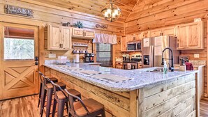 A wooden cabin kitchen with a large island, bar stools, and a sign indicating 'Lake'. - 'star Lite' Cabin: Hot Tub, Deck & Pool Table (Sevierville)