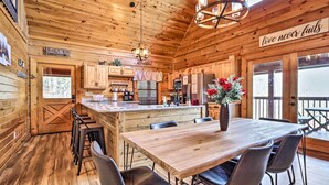 A wooden cabin interior with a kitchen, dining area, and a sign that reads "love never fails". - 'star Lite' Cabin: Hot Tub, Deck & Pool Table (Sevierville)