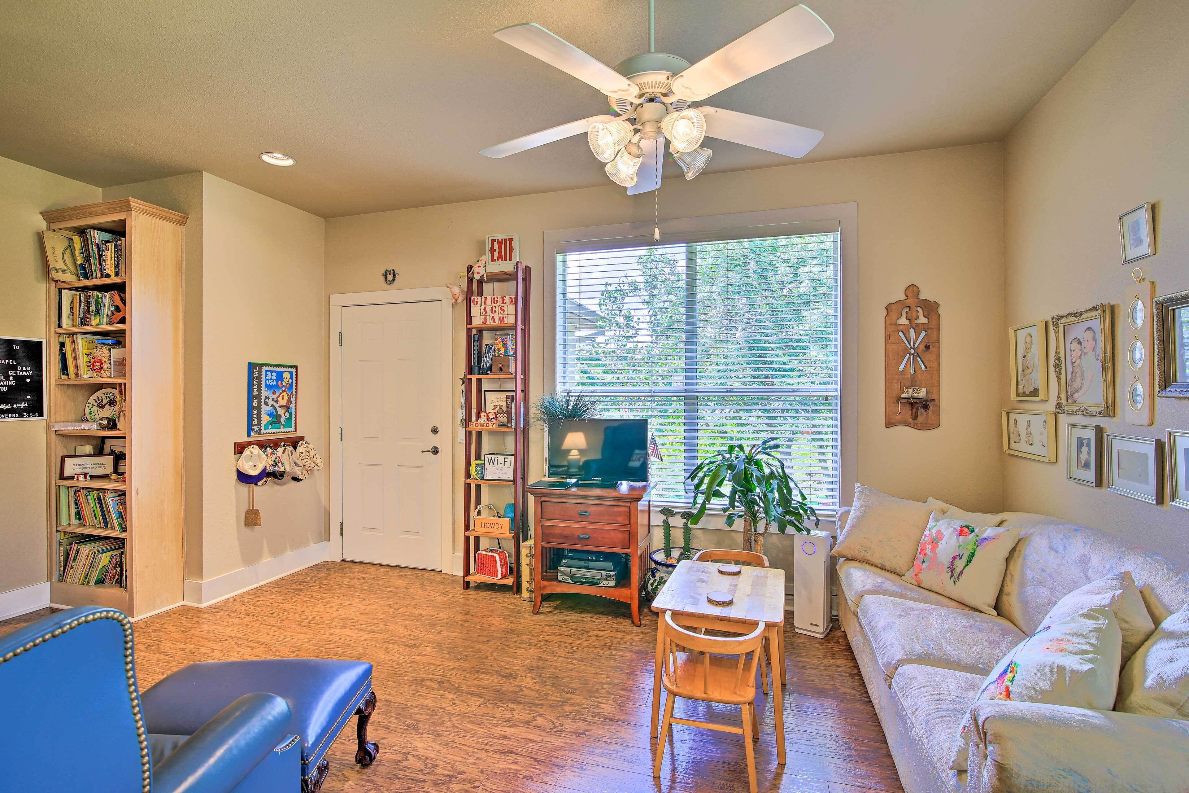 A living room with a ceiling fan, a bookshelf, a TV, a sofa, and a dining table.