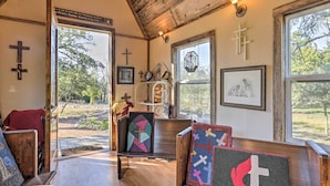 Una habitación acogedora con bancos de madera, techo de madera y ventanas grandes con vistas a árboles.