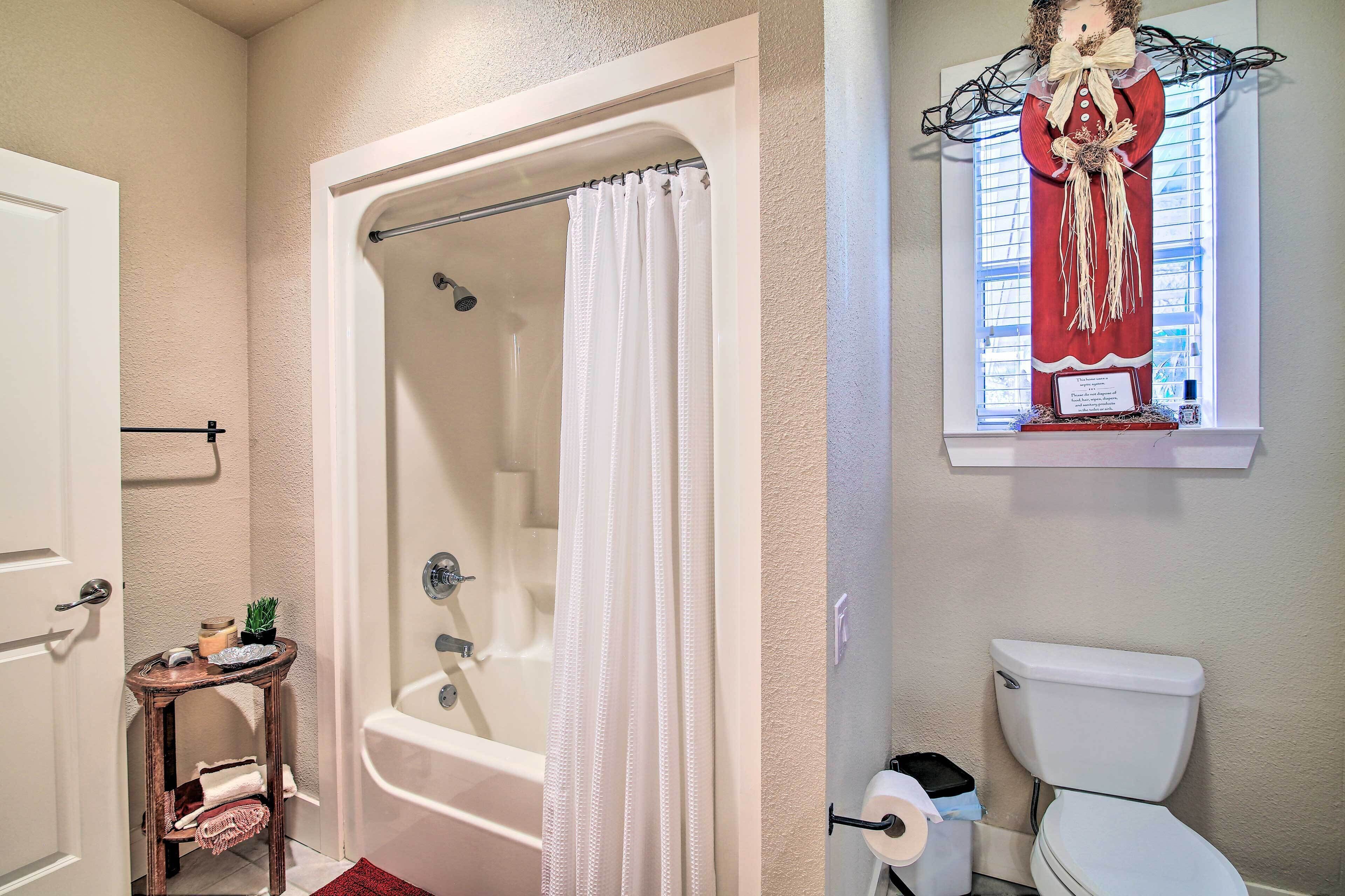 A bathroom with a bathtub, toilet, and a decorative window.