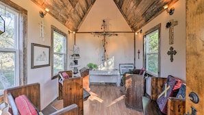 Una capilla rústica con bancas de madera, un altar de madera y una cruz en la pared.