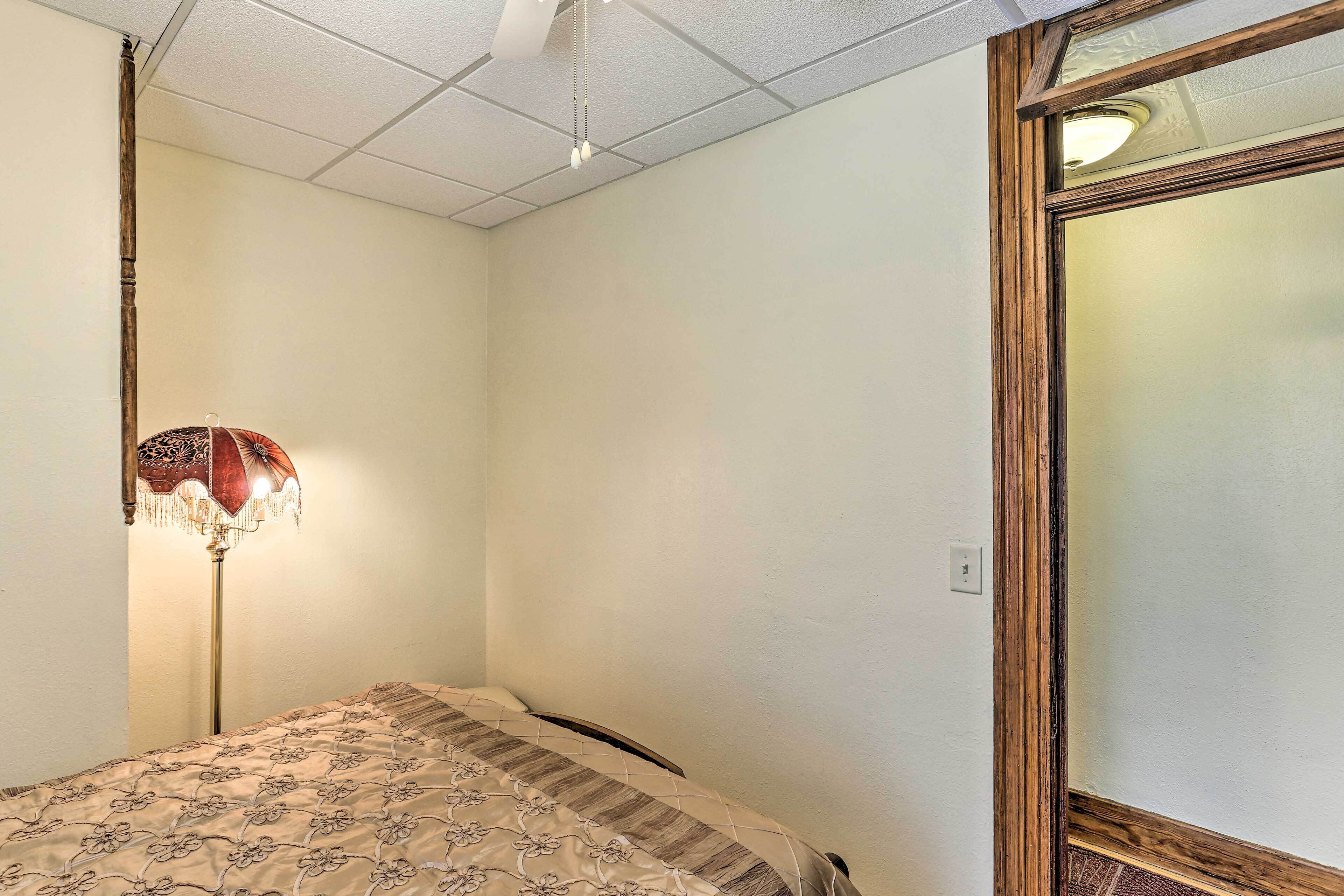 A bedroom with a bed, a floor lamp, and a window with a wooden frame.
