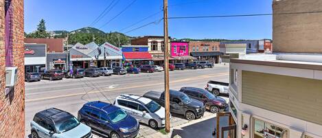 A street view with parked cars, buildings, and a clear sky.